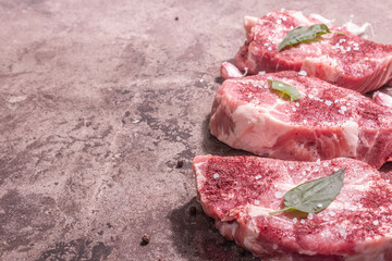 Raw pork meat, sliced cuts with dry sumac, fresh garlic and basil leaves