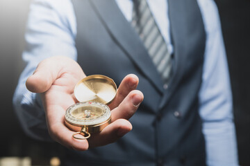 a man in a suit holding a golden compass