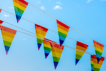Pennant rainbow flags waving on the air with blue sky and white clouds background, The symbol of...