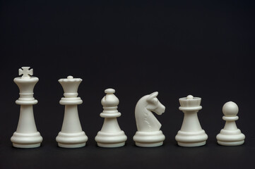 Set of white chess pieces on a black background. Chessmen. Table game. 