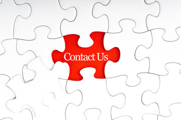 Fototapeta premium CONTACT US text with jigsaw puzzle on red background. Business and Support Concept