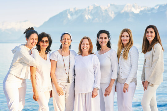 Group portrait of beautiful women posing outside with beautiful mountain landscape on background, wearing white clothes
