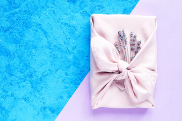 Gift wrapping Japanese furoshiki style on a pink and blue background.