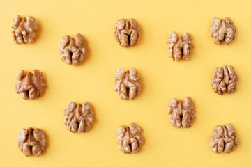 Halves of walnuts on a yellow background, pattern, background, top view.