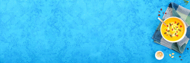 Pumpkin soup on blue concrete background, banner, top view, copy space.