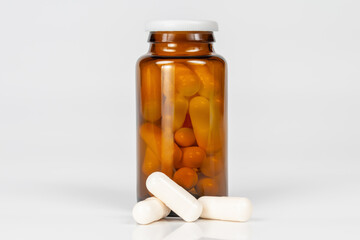 brown glass bottle with white capsules on white background with reflection