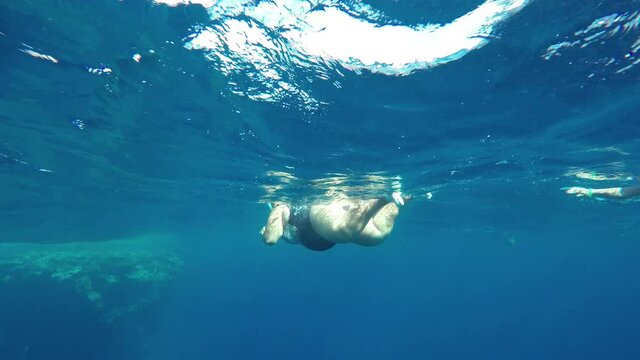 Fat overweight woman tourist snorkeler swims in the sea dangerous depth. Underwater photography video in the Red Sea.