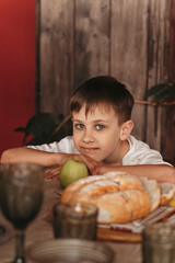 Fototapeta premium A boy in the kitchen with a green apple. Healthy food for children concept
