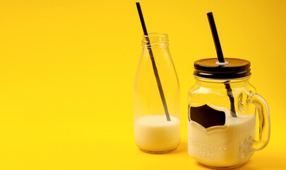 Healthy gluten and lactose free milk, full of vitamins, minerals and antioxidants, in a glass mug and bottle with a grain ingredient on a yellow background at breakfast. Copy space