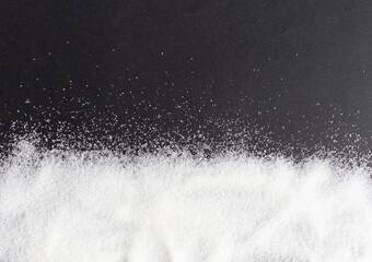 white sugar scattered  on black background