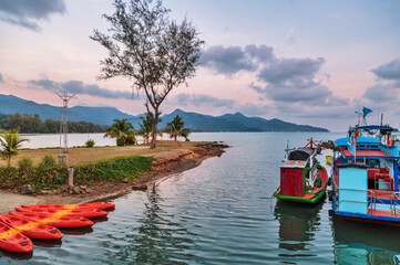 Kayaks and a boat in the bay at sunset time against the backdrop of mountains