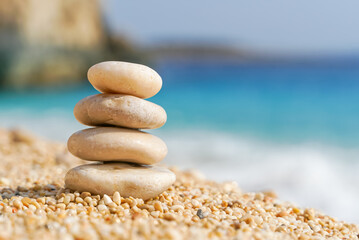 Fototapeta na wymiar Pyramid stones balance on the sand of the beach. Zen balance, minimalism, harmony and peace. Selective focus