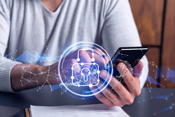 A programmer is browsing the Internet in smart phone to protect a cyber security from hacker attacks and save clients confidential data. Padlock Hologram icons over the typing hands.