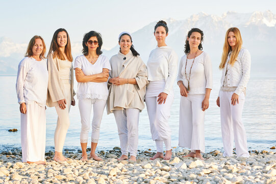 Group portrait of beautiful women posing outside with beautiful mountain landscape on background, wearing white clothes