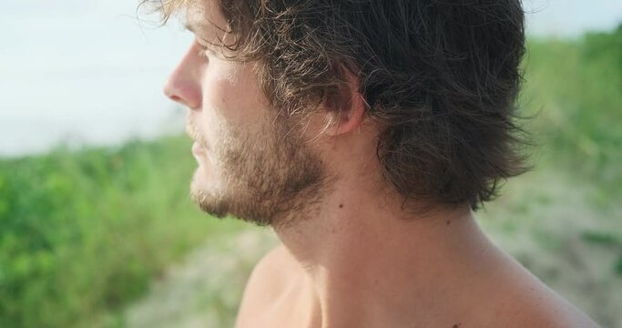 Close up portrait of young Brazilian man on the beach. Brazilian surfer stands outdoor, close up portrait