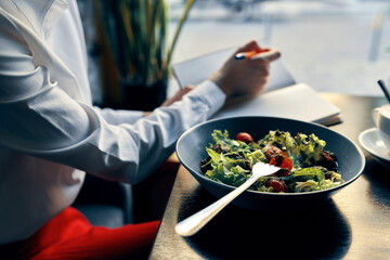 notepad with a pen in hand and salad in a plate restaurant cafe inscription
