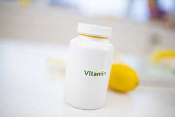 Bottle of vitamins on white table with limes and lemons as background