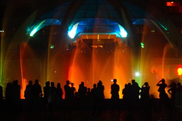 Fototapeta na wymiar People looking at fountain musical performance at night against casino. C