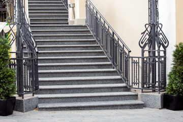 gray granite staircase with stone steps climbing upward with iron railing at the sidewalk from...