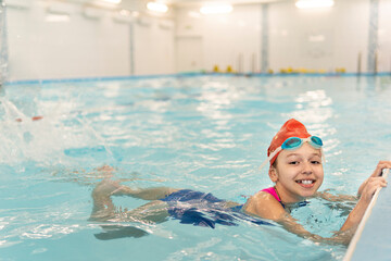 Girl learning to swim. Sports and entertainment for children. Swimming competition. Healthy lifestyle from childhood.