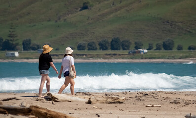 Two figures walking along Pouawa Beach, Gisborne region, New Zealand 