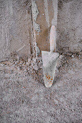 Trowel and adze in front of the recently made plastered wall by concrete. Red colors exist on handle of the adze made of wooden material. after construction works.