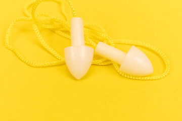 Silicone ear plugs for human ears on yellow background