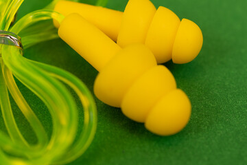 Silicone reusable ear plugs for human ears on green background