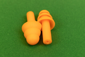 Silicone reusable ear plugs for human ears on green background