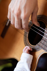 FATHER'S AND BABY'S HANDS ON A GUITAR