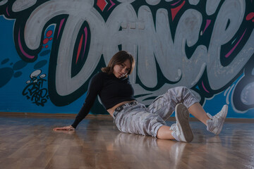 Fototapeta na wymiar Attractive young woman doing breakdance move over graffiti background