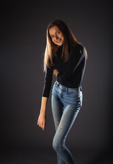 A fashionable young woman in black roll neck posing isolated on a dark background