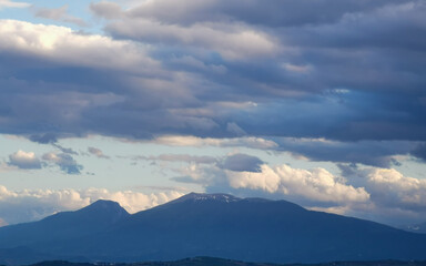 Grandi nuvole sopra le montagne dell’Appennino all’imbrunire in un cielo azzurro primaverile