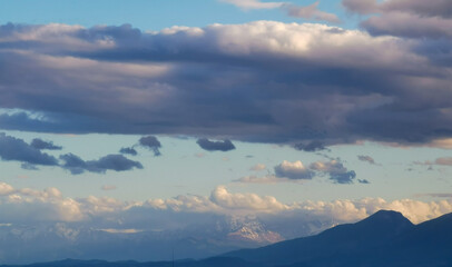 Fototapeta na wymiar Grandi nuvole sopra le montagne dell’Appennino all’imbrunire in un cielo azzurro primaverile