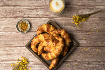Croissants and cappuccino on wood background