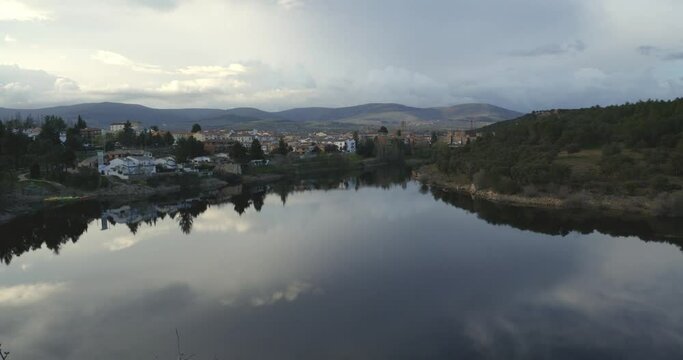 A wide view of the Buitrago del Lozoya, Spain. In the foreground appears the river, with calm waters, and in the background the town