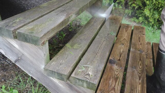 Man pressure washing wooden stairs