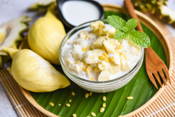 Asian Thai dessert tropical sweet durian peel with yellow bean on wooden plate and fresh mint leaves, Ripe durian rice cooked with coconut milk, Durian sticky rice summer tropical fruit food