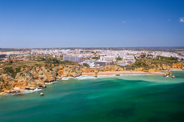 Dona Ana Beach in Lagos, Algarve - Portugal. Portuguese southern golden coast cliffs. Aerial view with city in the background.