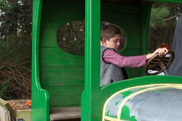 Young boy with Autism playing on an old car at a pumpkin patch;  pretend play with car steering wheel - obrazy, fototapety, plakaty