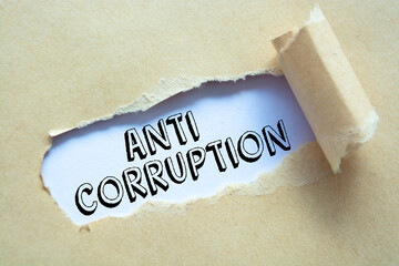 Text Anti Corruption appearing behind ripped brown paper.