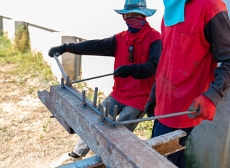 Workers use bending equipment to bend steel.