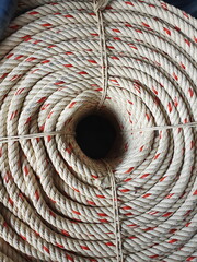Top view of a large manila rope woven into a valley or polypropylene rope wrapped in a red circle inside. Combined for convenient and neat use. Often used to hitch boats or lift heavy objects.
