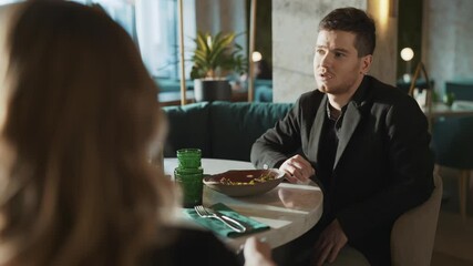 Portrait of suit wearing young adult business partners colleagues sitting at table in restaurant. Coworkers discussing working problems and current situation. Concept of lifestyle.