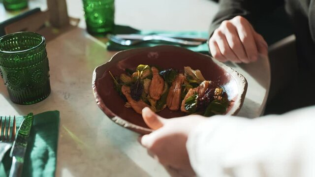 Cafe scene of waitress bringing order to table with business coworkers. Mask wearing girl putting dish on table. Colleagues discussing work, talking about current situation. Concept of coronavirus