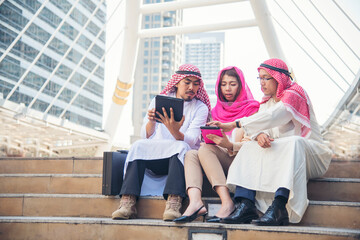 Fototapeta premium Digital marketing group arab people using smart tablet walking in modern muslim UAE city touch screen discussion. Entrepreneur Asian people smile talking with boss outdoors