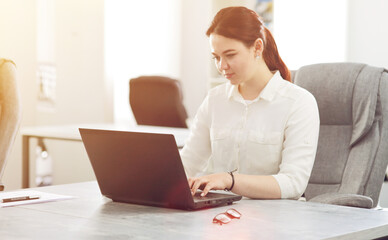 Young attractive business woman working in office smiling looking into laptop