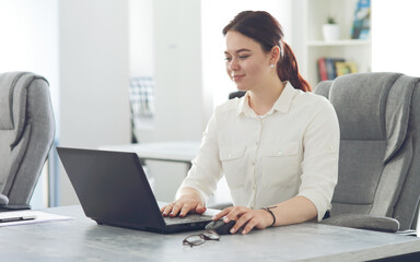 Young attractive business woman working in office smiling looking into laptop