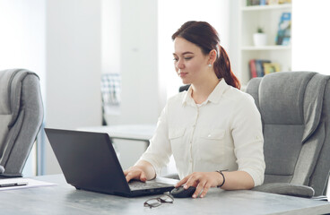 Young attractive business woman working in office smiling looking into laptop