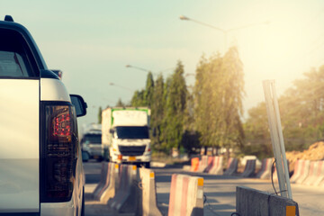 Luxury rear corner of  white car pickup truck on the road.  ฺBlurred other cars of drive on the road and  during the construction of the road, the barrier blocked the route along the way.